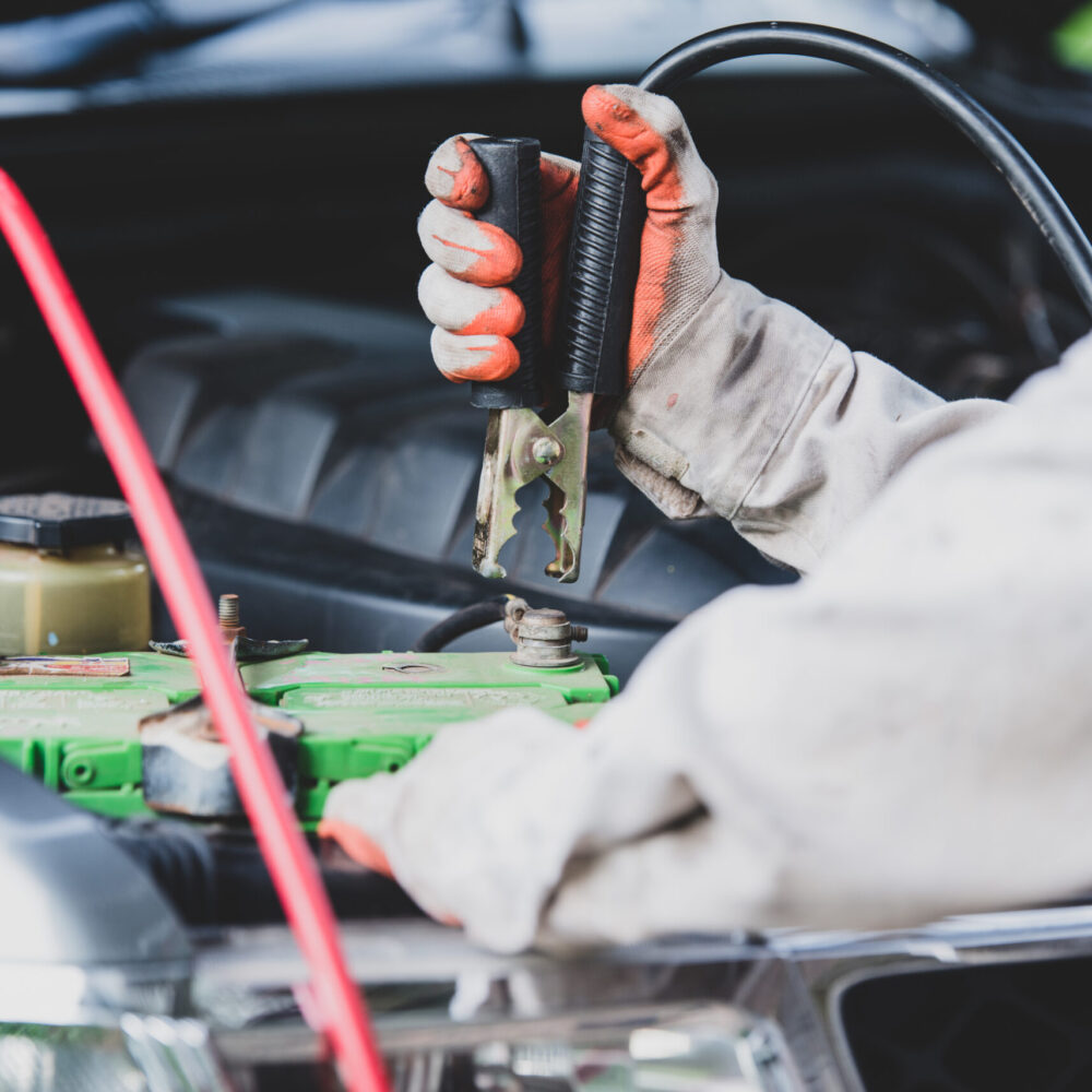 Car repairman wearing a white uniform standing and holding a wrench that is an essential tool for a mechanic