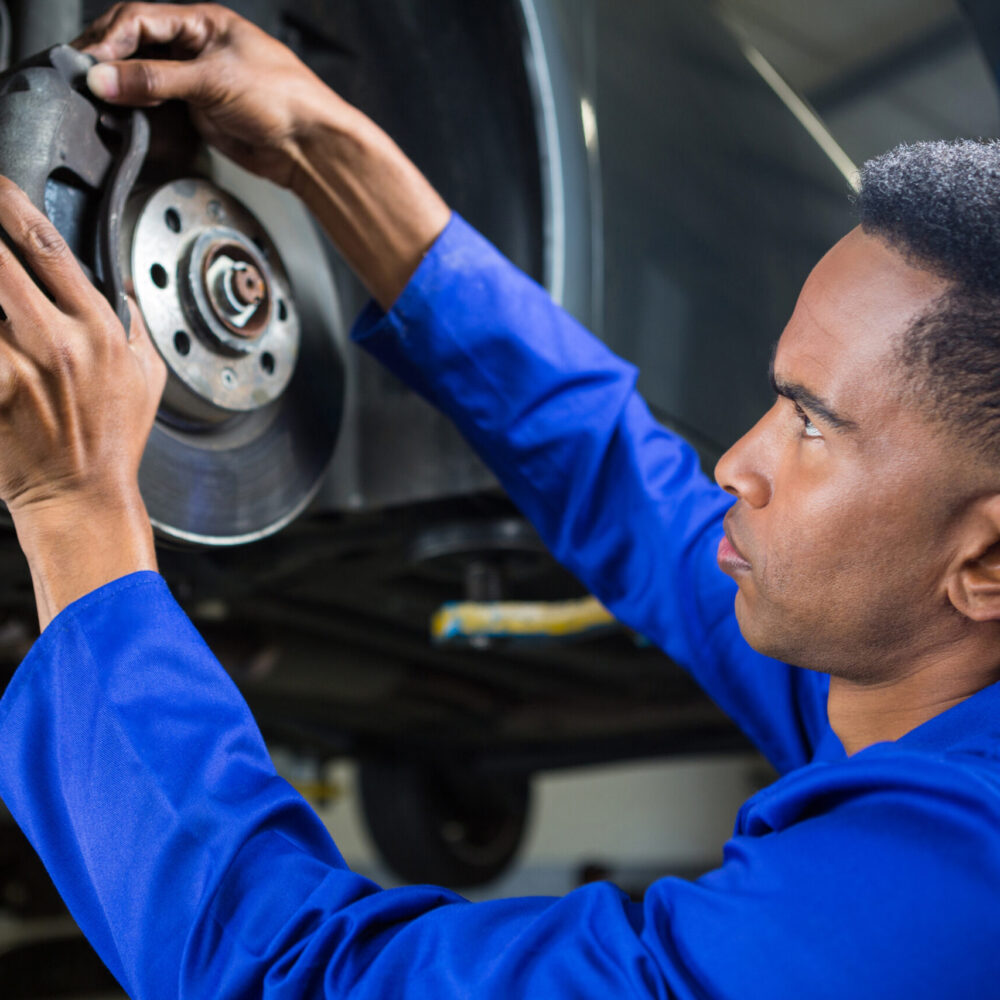 Attentive mechanic fixing a car brake at repair garage