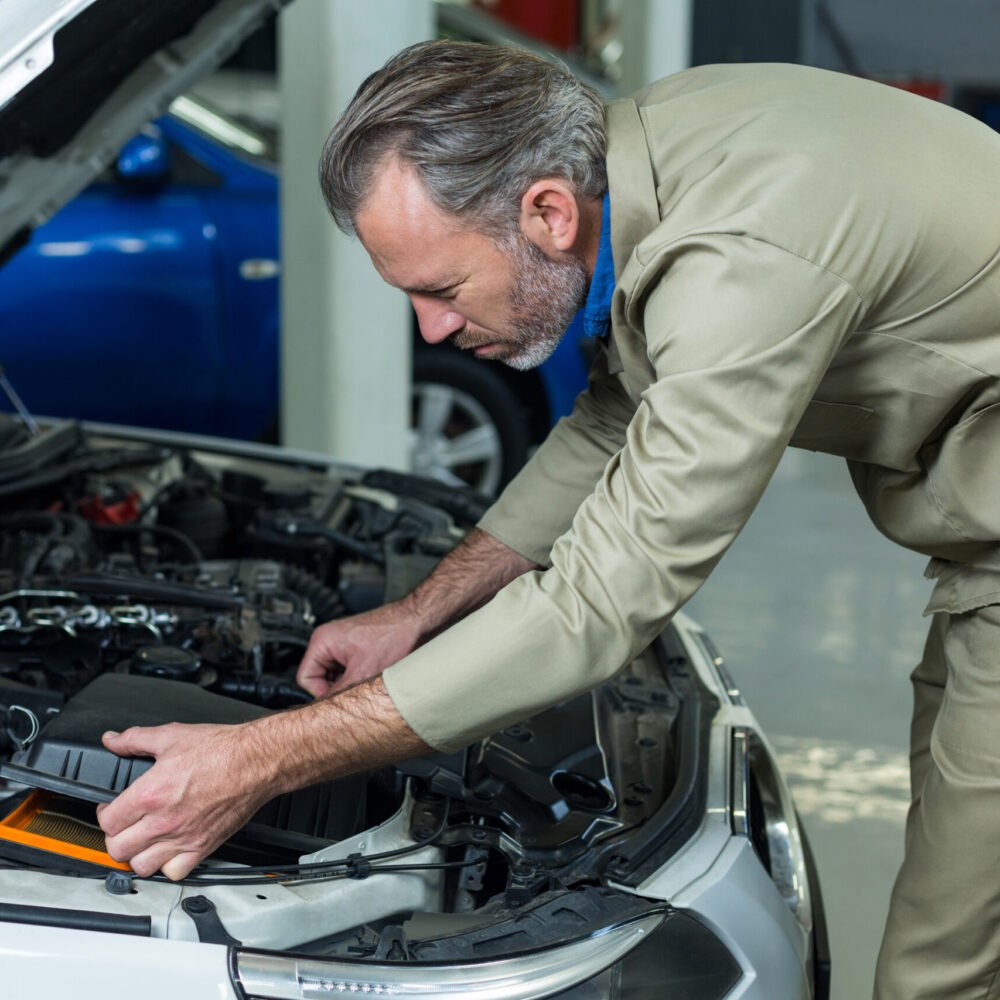 Mechanic servicing automobile car engine in repair garage